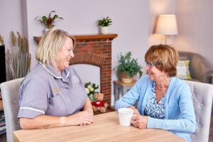 Herriot Hospice Homecare Healthcare Assistant at home chatting to patient.