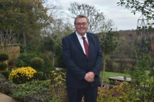 Tony Collins standing in the garden wearing a suit.